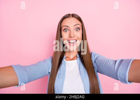 Photo of excited pretty young lady wear blue shirt smiling recording self video isolated pink color background Stock Photo