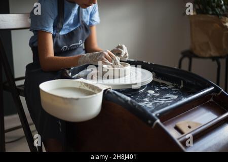 Hands of girl creating pot on potter's wheel. Traditional craft. Master class on modeling of clay on a potter's wheel in the pottery workshop. Making Stock Photo