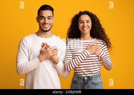 Gratitude Concept. Thankful Middle Eastern Couple Keeping Both Palms On Chest Stock Photo