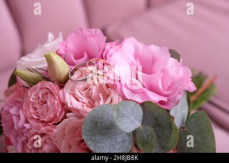 Two wedding rings of white and yellow gold on a bouquet of pink roses. Stock Photo