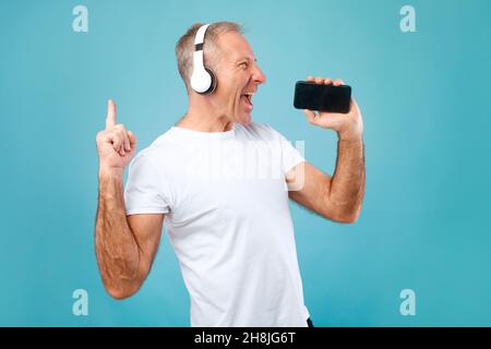 Happy mature man singing using smartphone as mic Stock Photo