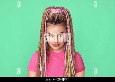 unsatisfied woman with dreadlocks on green background. Stock Photo
