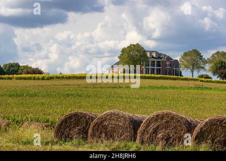 Gray, Tennessee, USA - September 18, 2021:  Agriculture field of grass hay and tobacco with a large home on a hill under cloudy skies. Stock Photo