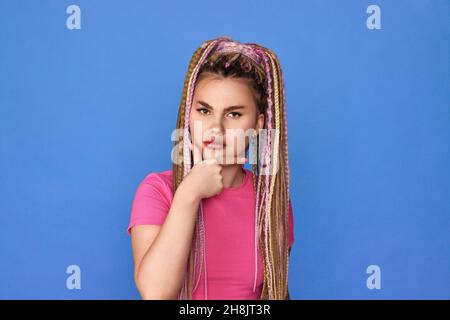 unsatisfied woman with dreadlocks on blue background. Stock Photo