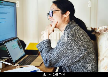 Businesswoman working from home, using multiple screens Stock Photo