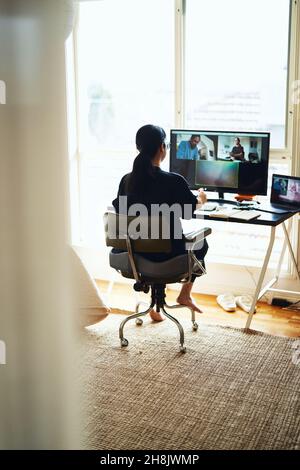 Businesswoman working from home, using multiple screens Stock Photo