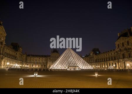 The famous Louvre Palace and its iconic glass pyramide at night, Paris, France Stock Photo