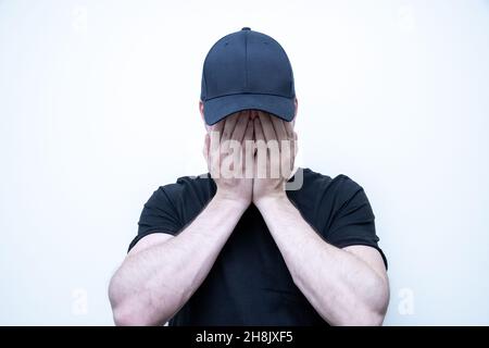 Young depressed man is covering his face with his hands Stock Photo
