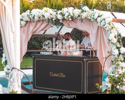 Decorated outdoor cocktail bar with two working barmen standing on the background of a pool Stock Photo