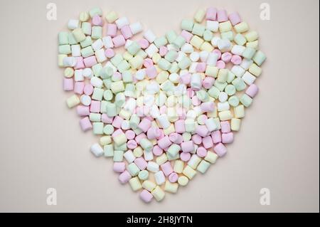 mini marshmallows lie in a heart shape on pastel background Stock Photo
