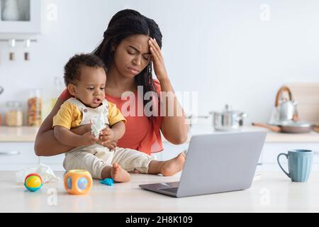 Maternity Stress. Young Black Mother Having Headache While Babysitting Her Infant Child Stock Photo