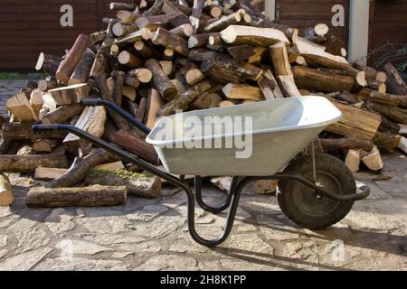 Pile of logs and a empty wheelbarrow Stock Photo