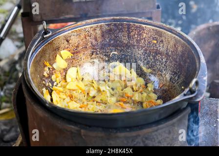 Cooking in nature while fishing. Old wood stove and cauldron. Cooking on an open fire. picnic on the hunt Stock Photo