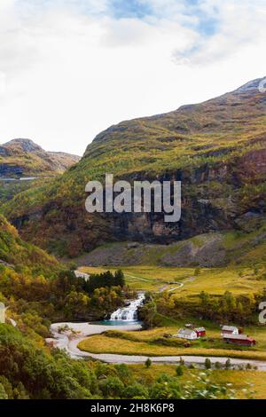 Landscape in Norway with mountains, waterfall and wooden houses. View from train Flamsbana which runs between Flam and Myrdal in Aurland in Western No Stock Photo