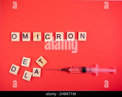 Omicron variant replaces Delta. Emergence of new dangerous strain of coronavirus COVID-19 Omicron. Syringe. Words omicron delta on colored red backgr Stock Photo