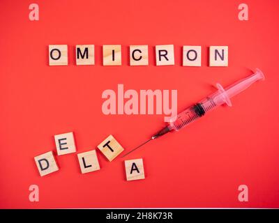 Omicron variant replaces Delta. Emergence of new dangerous strain of coronavirus COVID-19 Omicron. Syringe. Words omicron delta on colored red backgro Stock Photo