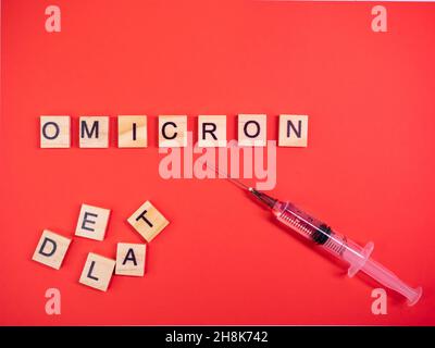 Omicron variant replaces Delta. Emergence of new dangerous strain of coronavirus COVID-19 Omicron. Syringe. Words omicron delta on colored red backgro Stock Photo