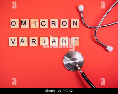 Omicron variant replaces Delta. Emergence of new dangerous strain of coronavirus COVID-19 Omicron. Phonendoscope. Words omicron variant on colored red Stock Photo