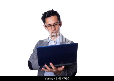 Modern young businessman wearing glasses and typing on laptop, isolated on all-white background. Latin man wearing modern stylish clothes. Stock Photo