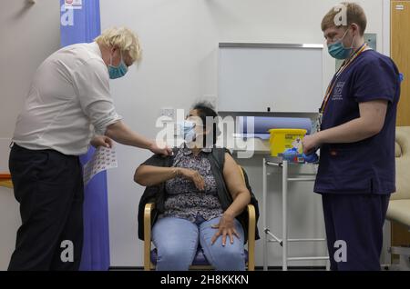 LONDON, Dec. 1, 2021 (Xinhua) -- British Prime Minister Boris Johnson meets a citizen having her booster shot at a COVID-19 vaccination site at Lordship Lane Primary Care Center in London, Britain, Nov. 30, 2021. Boris Johnson said Tuesday that everyone over the age of 18 will be offered a booster vaccine by the end of January and another lockdown 'extremely unlikely'. (Andrew Parsons/No 10 Downing Street/Handout via Xinhua) Stock Photo