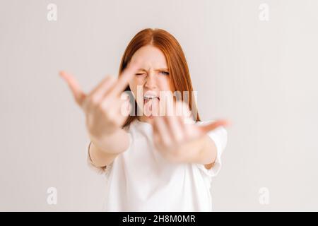 Portrait of excited young woman showing middle fingers on both arms, gesture of disrespect and hate, doing bad expression. Stock Photo