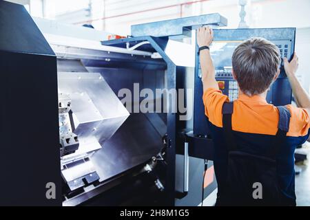 Worker use tool on lathe machine on factory floor. Industry portrait people. Stock Photo