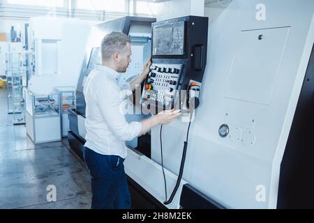 Young male engineer operating CNC machinery in iron metal factory Stock Photo