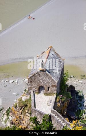 top view on chapel at Mont Saint michel, Normandy, France. Two tourists prefer to tan at the beach instead of visiting the site. Stock Photo