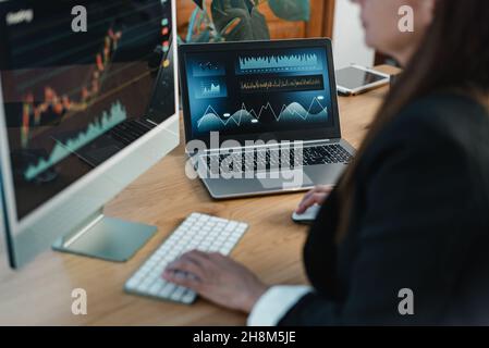Crop trader at table with laptop and computer screen Stock Photo