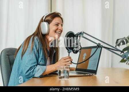 Happy woman recording podcast and speaking in mic Stock Photo