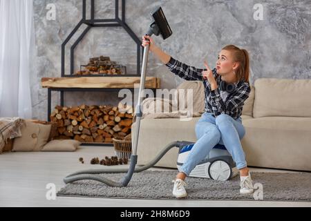Young woman with cleaning equipment ready to clean house, sitting on couch. Fatigue Stock Photo