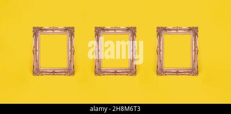 three empty ornate gold picture frames on yellow wall background Stock Photo
