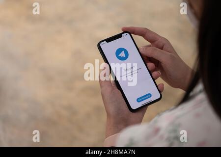 CHIANG MAI, THAILAND, NOV 14, 2021 : Woman hand holding iPhone X with social networking service Telegram on the screen. iPhone 10 was created and Stock Photo