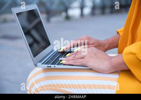 Close up of businesswoman hands with false nails working with a laptop outdoor. Stock Photo