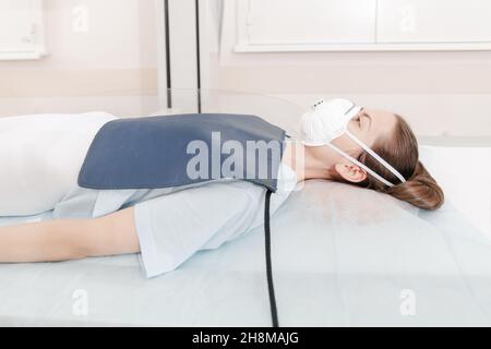 Doctor taking x-ray of patient lying on gurney. Hospital radiology room. Technician adjusting an x-ray machine. Female lying on a bed is scanning Stock Photo