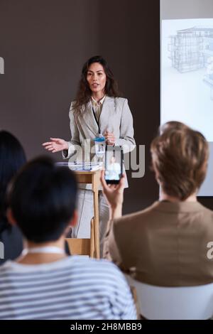 Young businesswoman performing with report for group of business people at the seminar Stock Photo