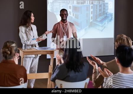 Young people presenting report for business people, they showing the project of new building on the big monitor at the seminar Stock Photo