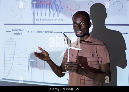 African young engineer holding new project in his hand and talking about it at conference Stock Photo