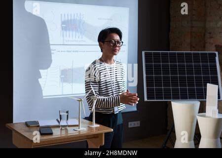 Asian young architect in eyeglasses talking about new innovation while standing new the big monitor at office Stock Photo