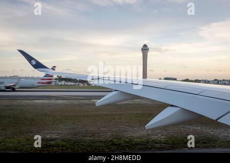 A view from the window over the wing of an Air France jet taxiing as an American Airlines flight lands at Miami International Airport in Miami, Florida. Stock Photo