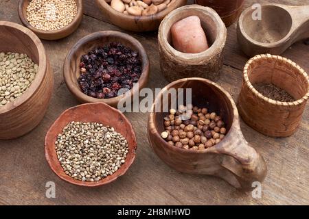 Medieval food in wooden and ceramic dinnerware. Cereals, seeds, dried berries, beans, salt and other foods Stock Photo