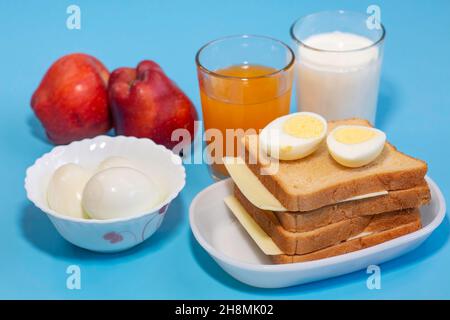 Healthy Indian breakfast with brown bread, cheese and sliced egg with fruit juice apples and milk in closeup macro view Stock Photo