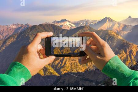 Tourist hiker captures the scenic Himalaya mountain landscape on his mobile at Sarahan, Himachal Pradesh, India Stock Photo