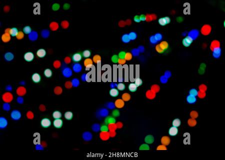 Multicolored bokeh of Christmas garlands on a Christmas tree at night on street Christmas Eve and New Years. Bright flashes of colored lights, bokeh t Stock Photo
