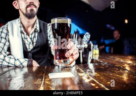 Expert Female bartender formulates a cocktail while standing near the bar counter in bar Stock Photo