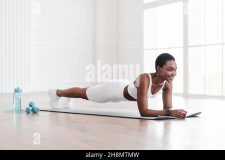 Young smiling black woman doing plank on yoga mat Stock Photo