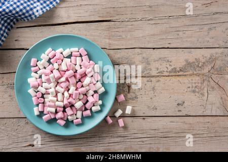 Sweet marshmallows topping in a blue plate on wooden table Stock Photo