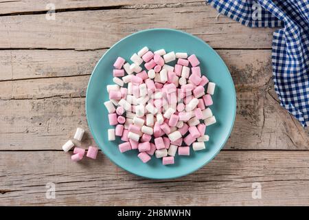 Sweet marshmallows topping in a blue plate on wooden table Stock Photo
