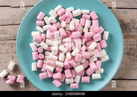 Sweet marshmallows topping in a blue plate on wooden table Stock Photo