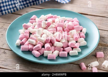 Sweet marshmallows topping in a blue plate on wooden table Stock Photo